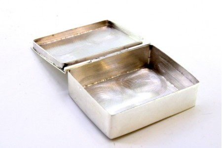 Caixa de comprimidos em prata lisa de forma quadrada e tampa basculante.